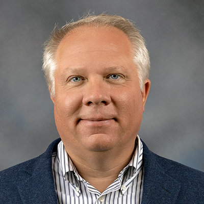 John Prostko headshot White hair blue eyes smiling at camera