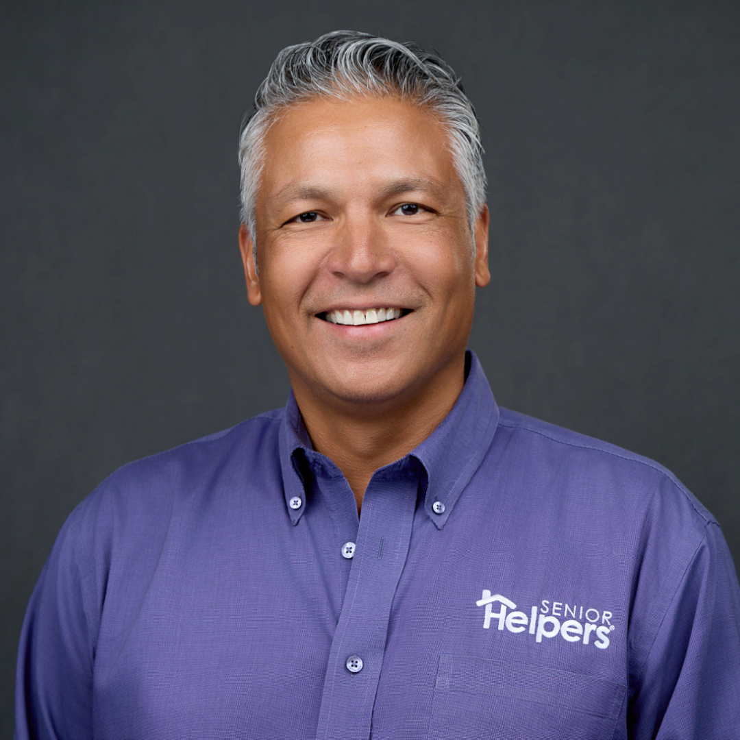 black background with man wearing purple shirt smiling