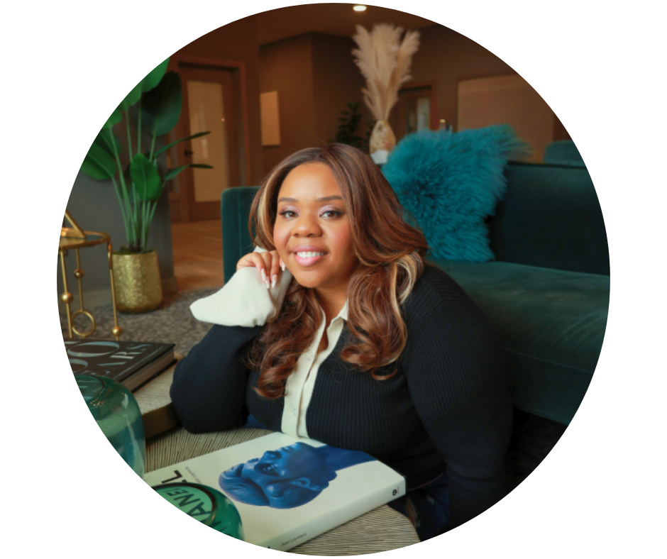 Photo of keynote speaker, Carla Williams, smiling at a table with a book surrounded by plants