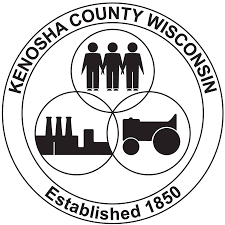 Circular black and white logo for Kenosha County including image of people, transportation and industry