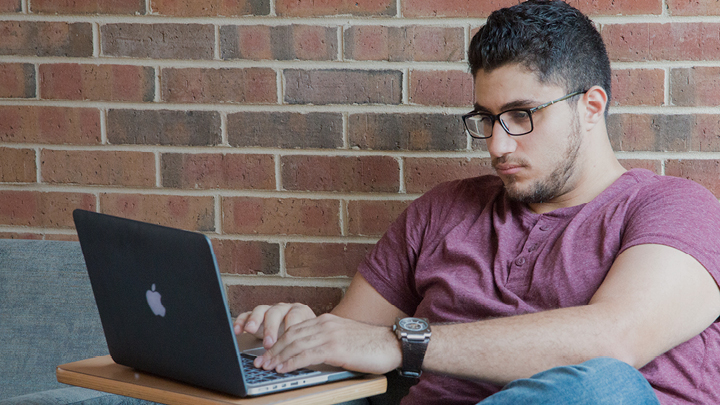 image of a male focused on his laptop in a casual setting