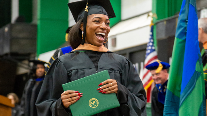 Image of a woman walking on commencment with her graduate garb