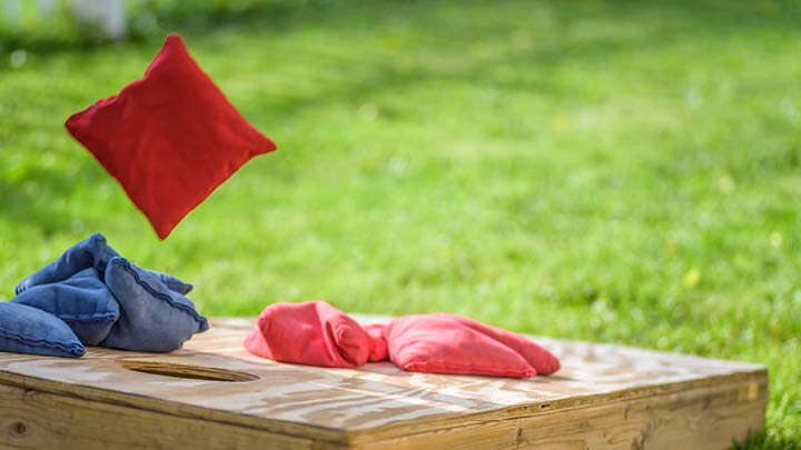 Red and Blue corn hole beanbags outside being thrown