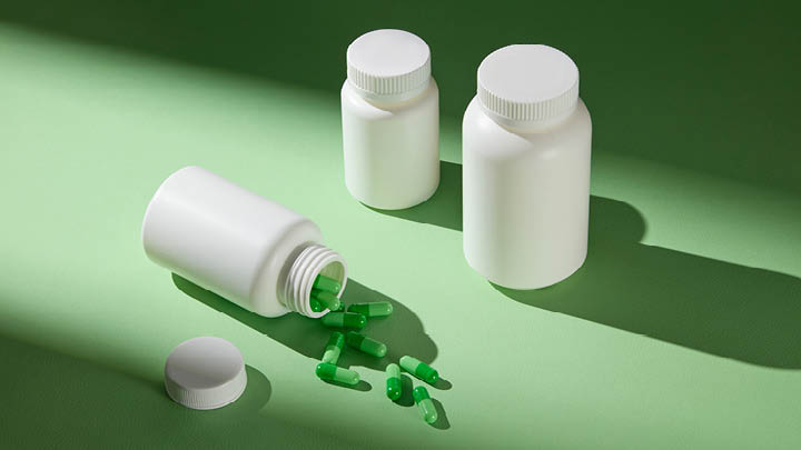 decorative white pill bottles with green pills on green background