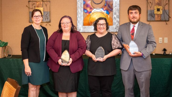 Awardees from the 2025 Distinguished Alumni Awards smiling and holding glass awards.