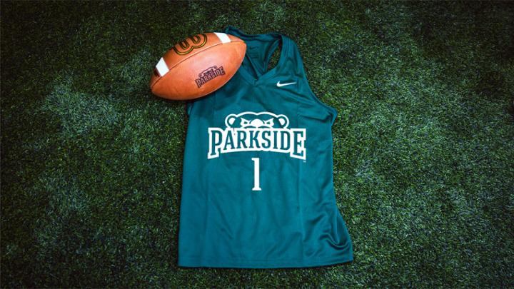 Image of a jersey and a football resting on turf