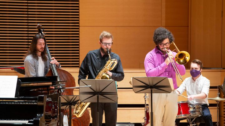 Three students playing instruments on a stage.