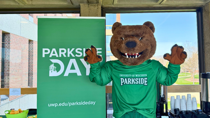 Ranger Bear posing next to a Parkside Day stand up banner on the Bridge at UW-Parkside