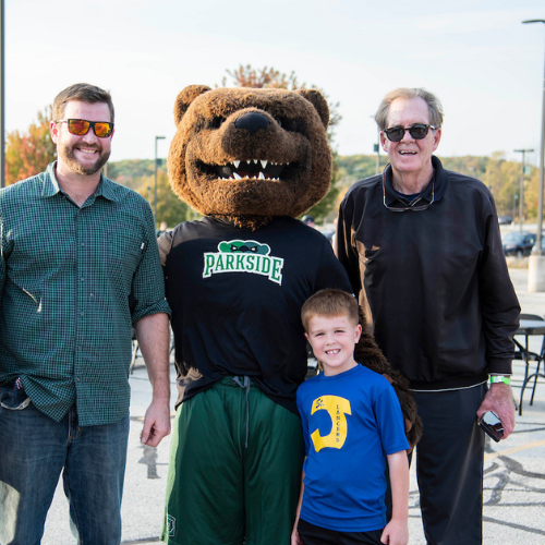 2 adult men with boy posing with Ranger Bear