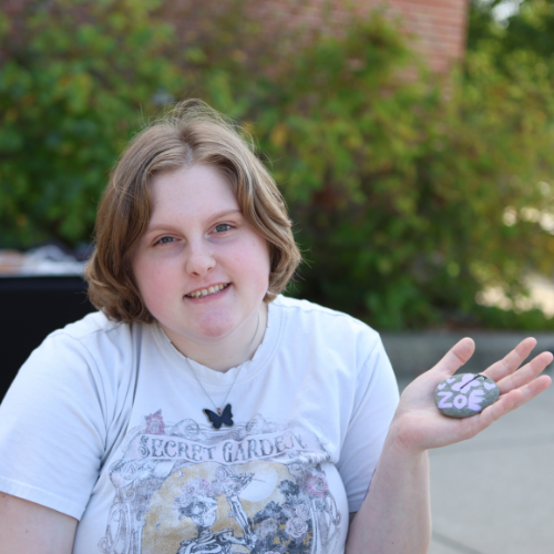 Girl outside wearing a white tshirt holding a rock that says Zoe