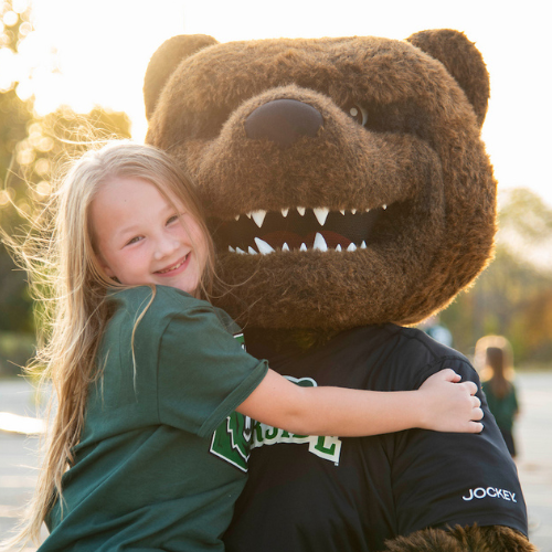 Ranger bear holding child at sunset