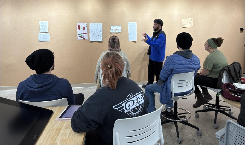 Carlo Giardina leading a group critique about mural sketch ideas in Carey Watter’s senior capstone class for graphic design majors, “Digital Portfolio”. Photo by Janet Jurado.