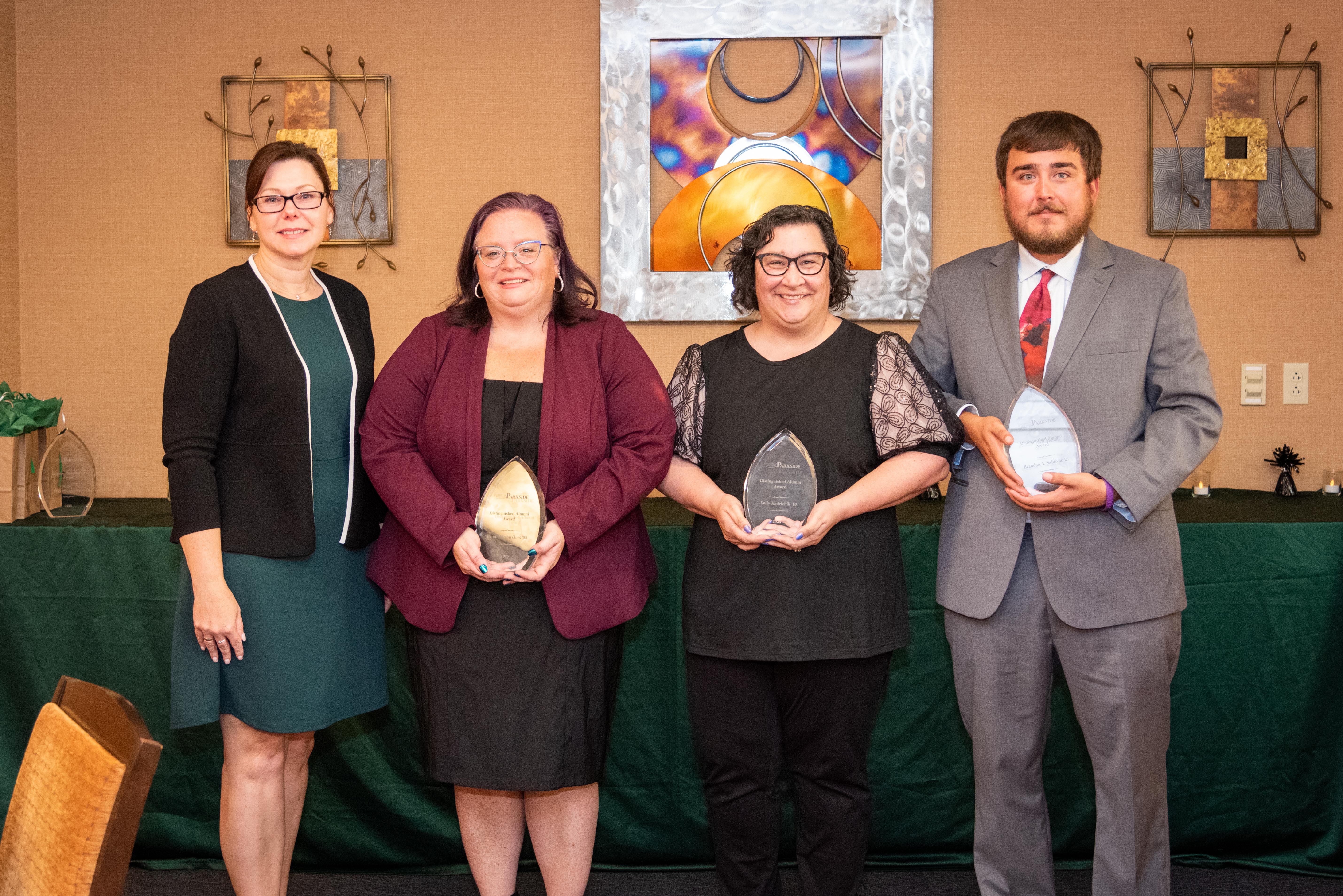 Awardees from the 2025 Distinguished Alumni Awards smiling and holding glass awards. 