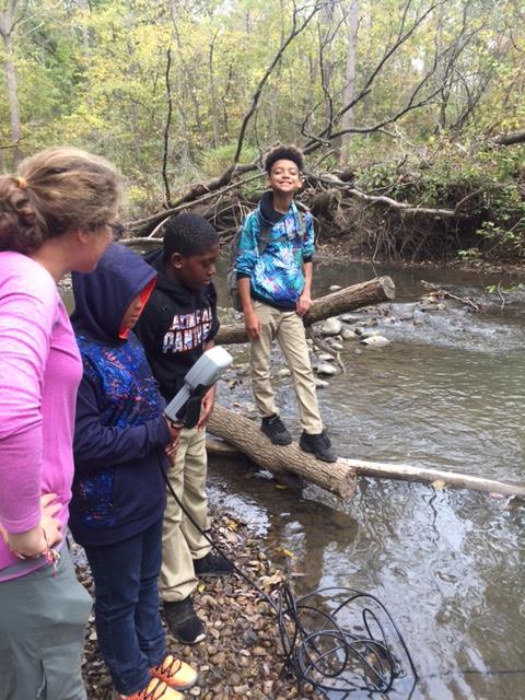 Student poses for photo while Laura Schulz helps other students.