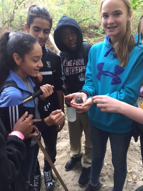 Students showing off a piece of matter that they dug up.