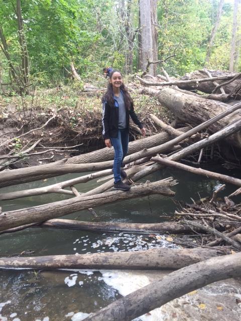 Student poses for camera while exploring the logs.