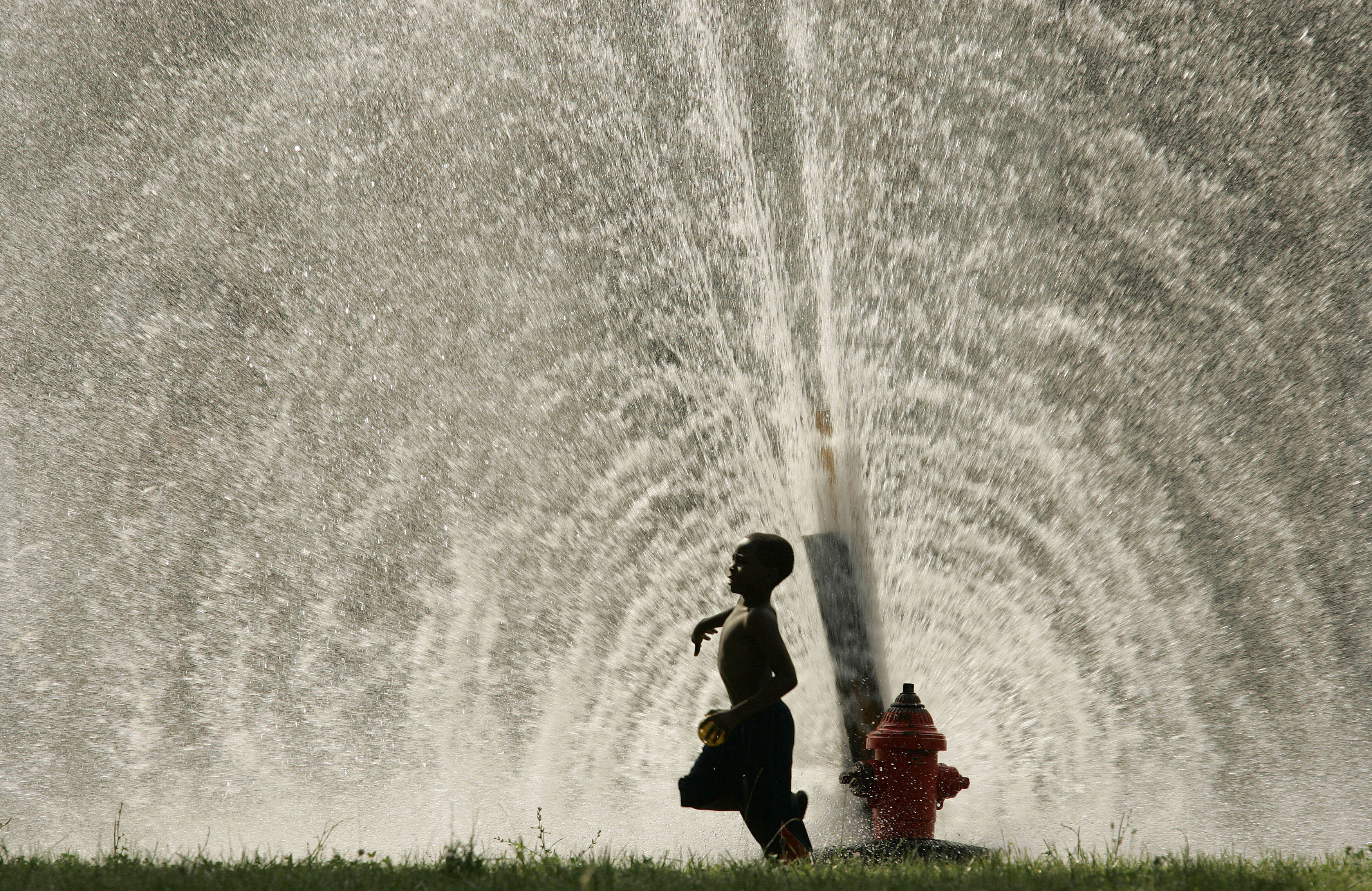Photo by Al Fredrickson: Boy prances through summer fire hydrant spray.   Light crystallizes magically through a water cascade   “A boy runs past spray from an illegally opened fire hydrant in Milwaukee, Wisconsin as people seek relief from a heat wave.