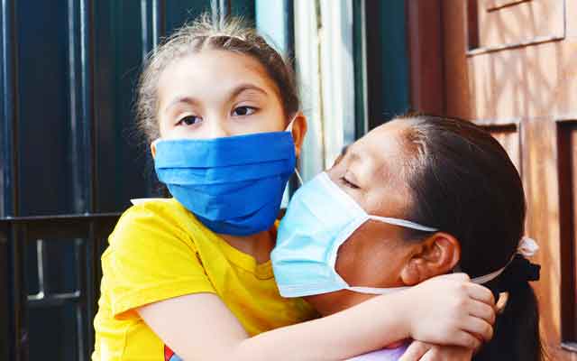 Native American girl and mom embrace wearing masks Native American girl and mom embrace wearing masks