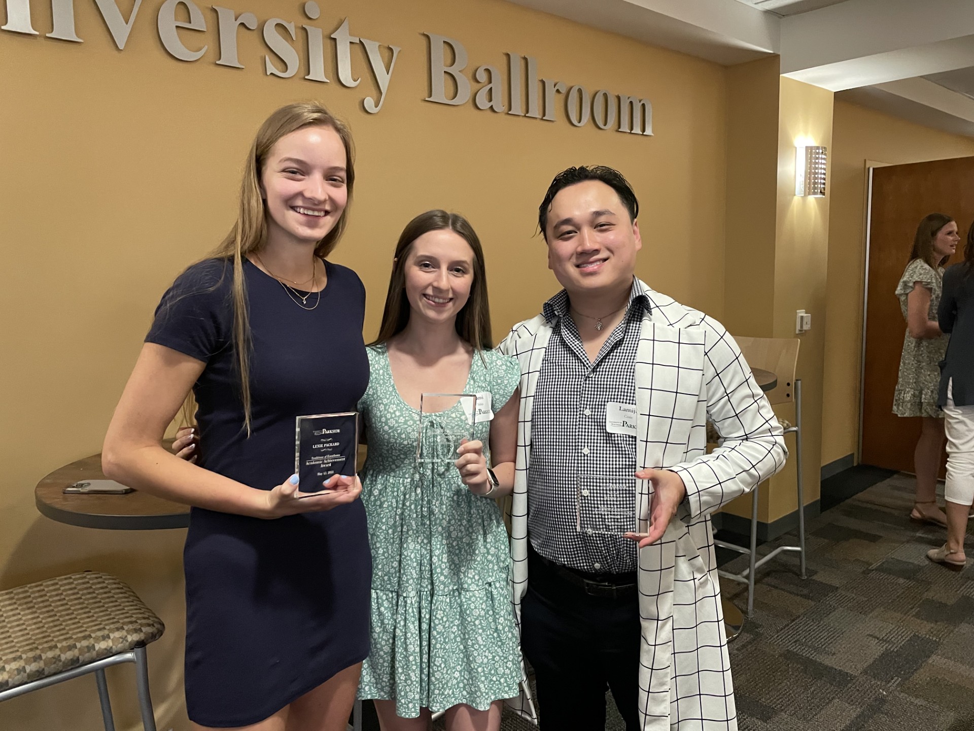 Three students smiling and holding awards