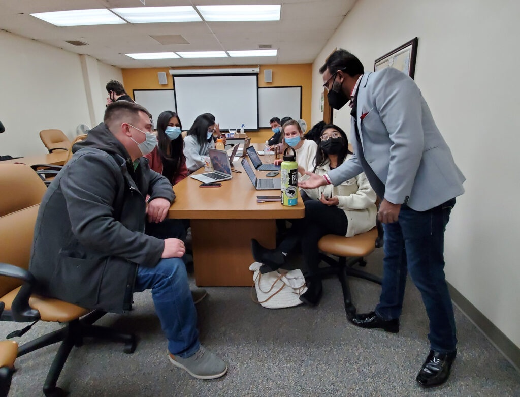 Nick Koenen, left, and Dr. Abey Kuruvilla, right, go over strategy with MBA business operations class at UW-Parkside.