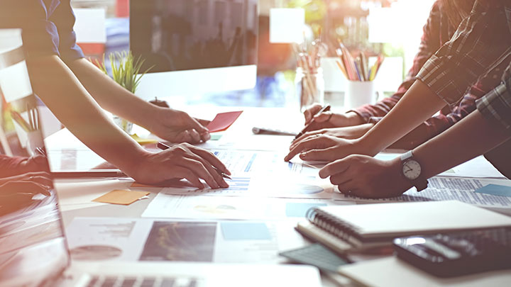 Image depicts people working together over a desk