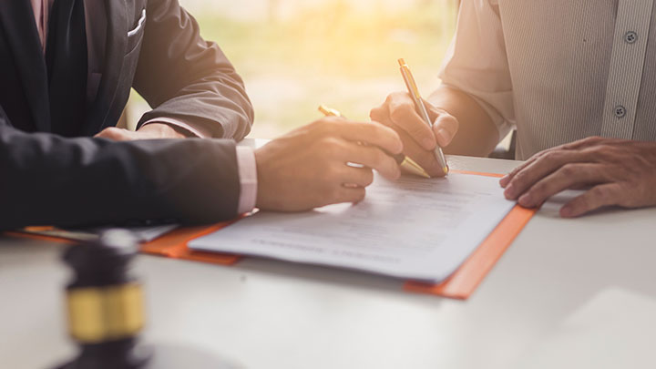 Image depicts two people writing on a document