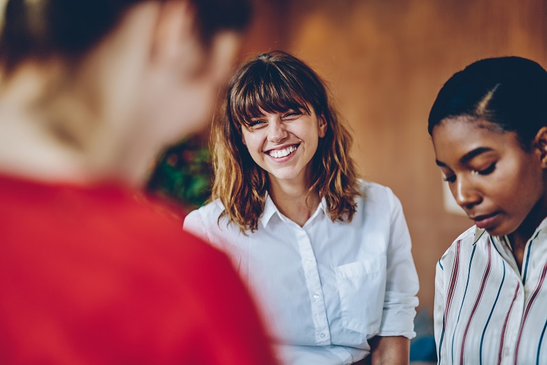 curly hair woman laughing with other individuals curly hair woman laughing with other individuals