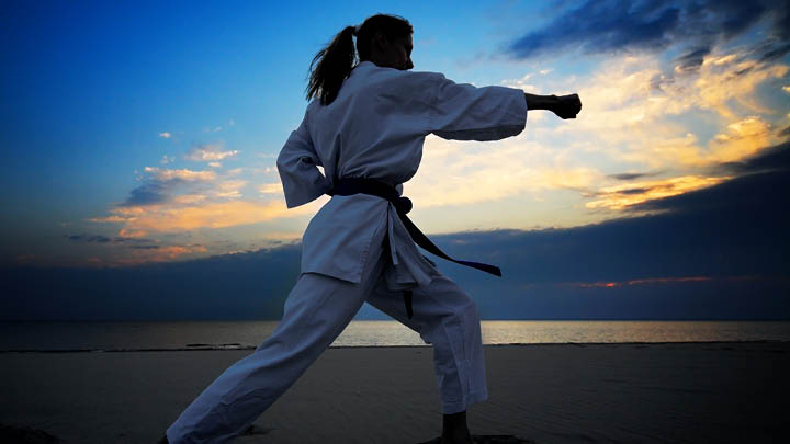 image of a woman in Karate garb with sunrise behind