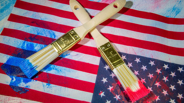 image of a usa flag with paintbrushes, one with red paint, onewith blue