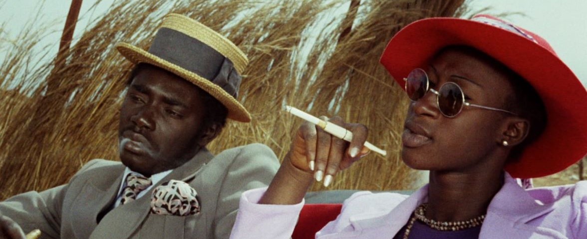Touki Bouki Two people smoking and sitting in a hay field
