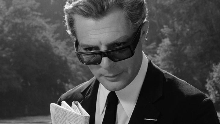 B&amp;W image of a man holding a folded newspaper and looking down over sunglasses