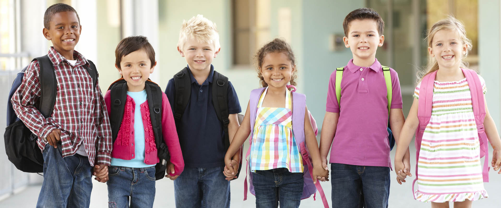 Children with backpack holding hands and smiling