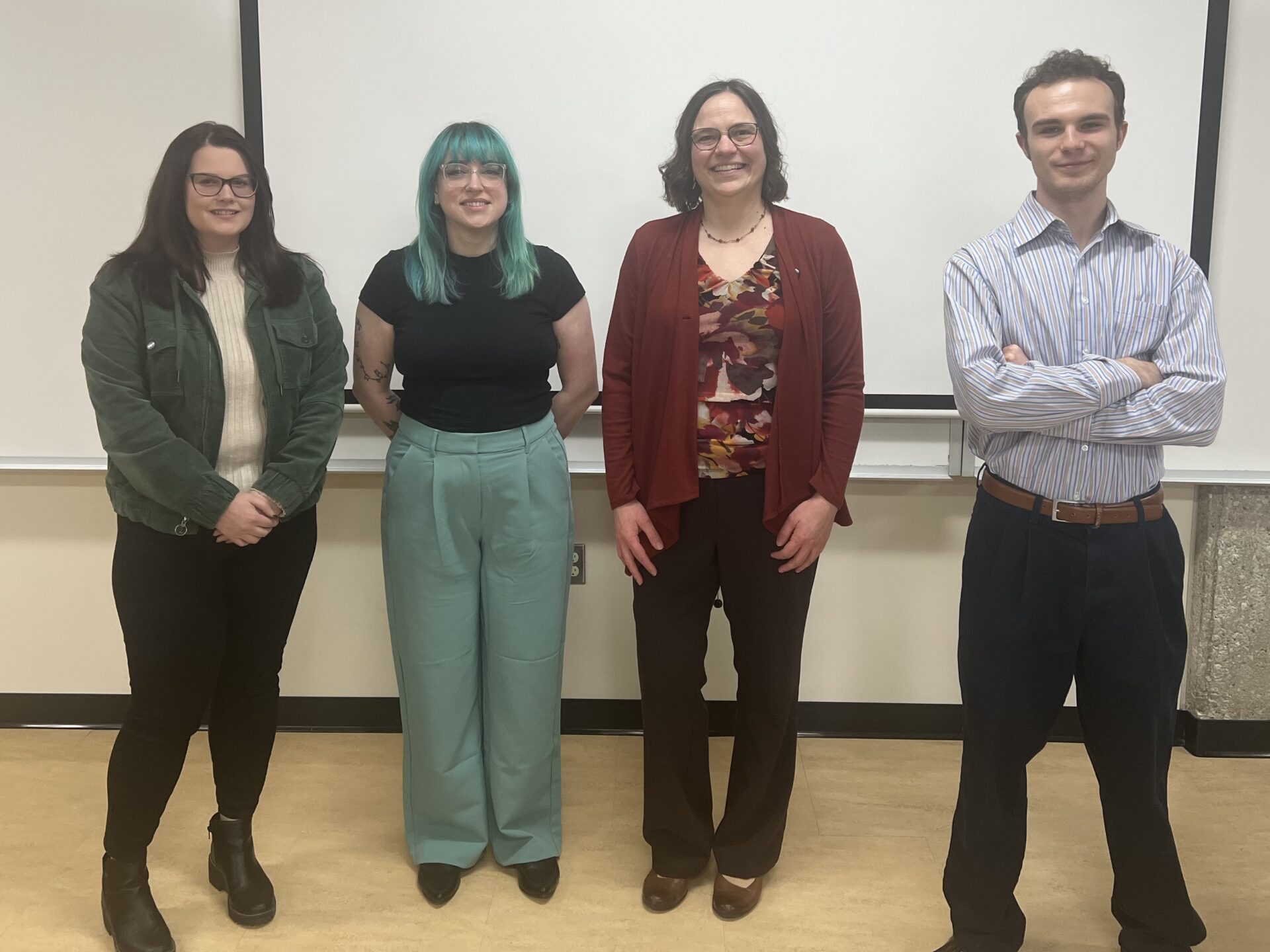 Community Engagement Specialist Amy Garrigan and 3 Civic Internship Program students stand in a classroom in Fall 2023