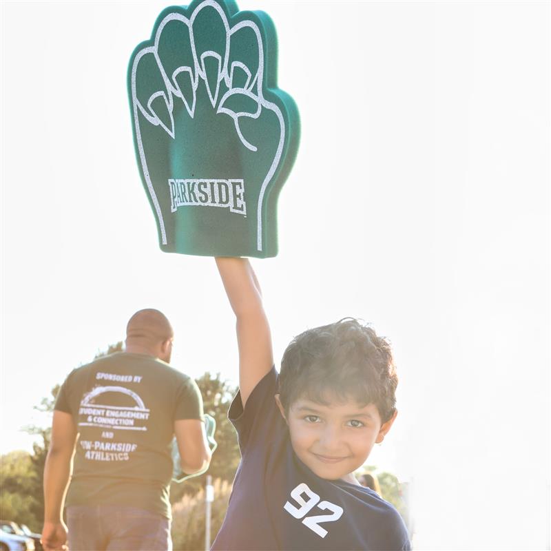 A little boy raising a parkside ranger bear claw up at sunset.
