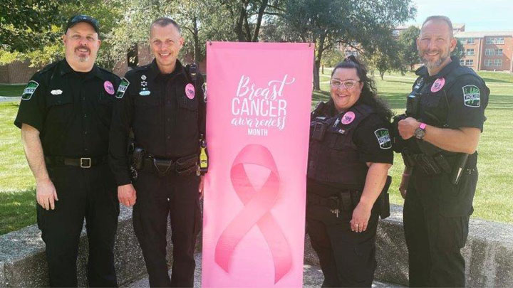 Officers posing with a Breast Cancer Awareness banner.