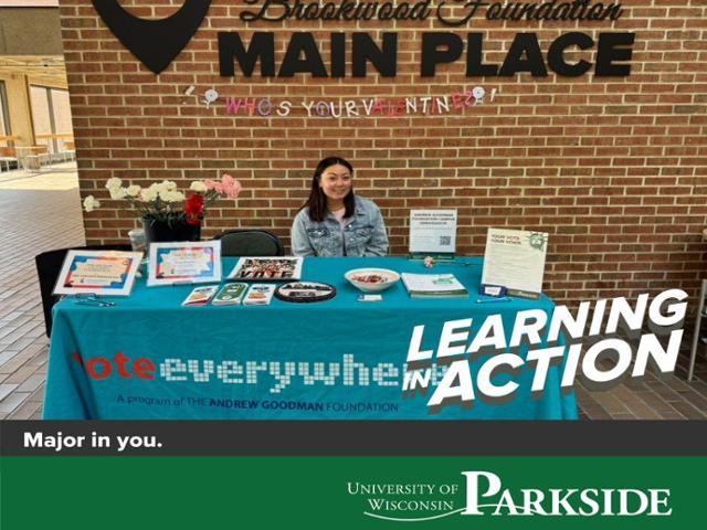 Vanessa Reynoso sits at a table decorated for Valentine's Day as she connects students with voter registration information.