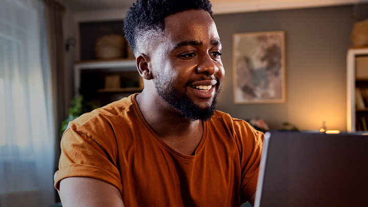 Image of black male college student looking at a laptop